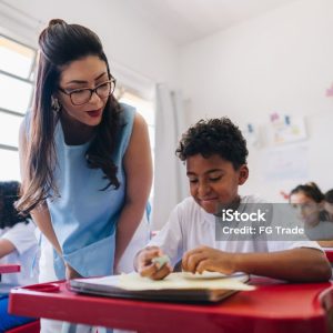 Teacher teaching her student on classroom at school